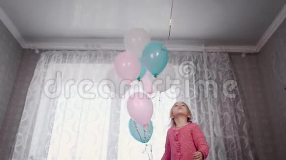 可爱的金发女孩站在父母的床上玩充满氦气的气球但只有一只白色的视频的预览图