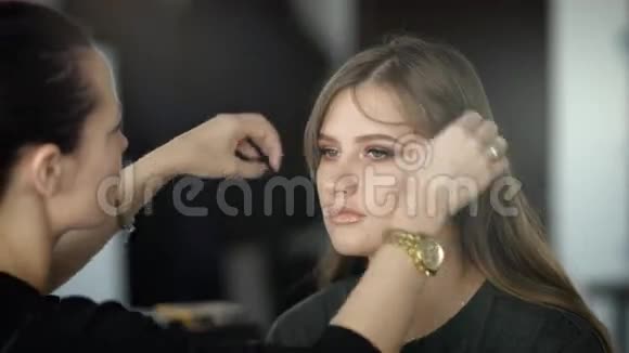在美容院的主人整理头发给她最好的朋友化妆在年轻女子手中的黄金视频的预览图