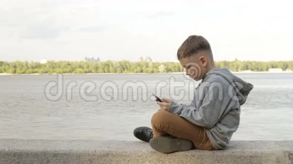 一个男孩正在海边的平板电脑上玩耍视频的预览图