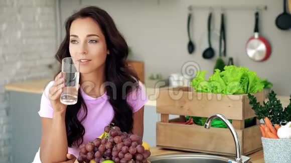 厨房里的年轻女人饮用水视频的预览图