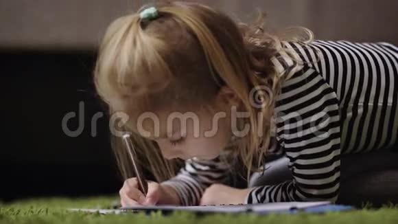 一个漂亮的小女孩穿着条纹套头衫在托儿所里用棕色铅笔画画小公主正在玩视频的预览图