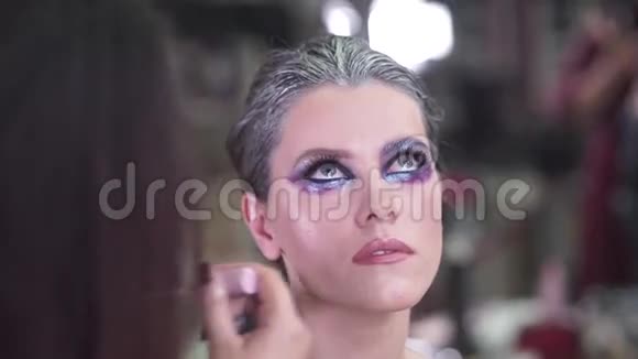 画眉毛和眼睛化妆师将化妆应用于一个有吸引力的年轻模特进行拍照视频的预览图