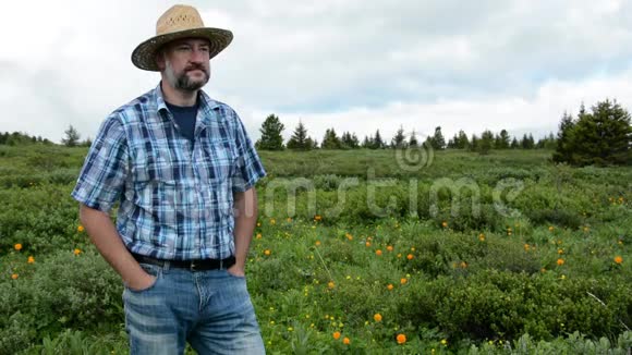 一个戴着草帽的农夫戴着一顶戴着鲜花的高山田野背景视频的预览图