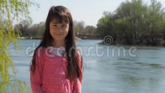 河边的女孩水边长着头发的小女孩春天阳光明媚的一天视频的预览图