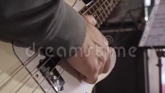 在舞台上演奏低音吉他的年轻人的手指上合上视频的预览图