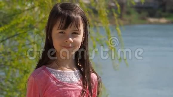 河边的女孩水边长着头发的小女孩春天阳光明媚的一天视频的预览图
