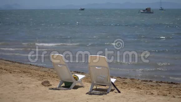 两把空塑料椅子放在沙滩上视频的预览图