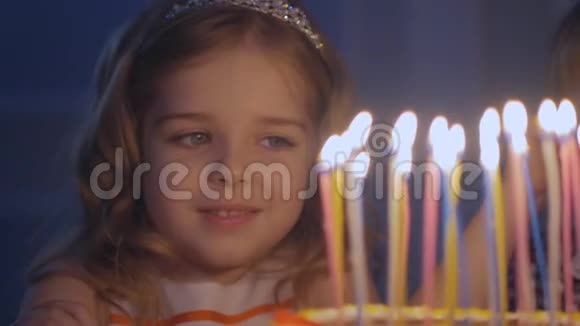 小美丽的女孩正在缓慢地在生日蛋糕上吹九支蜡烛一个快乐的小女孩看着视频的预览图