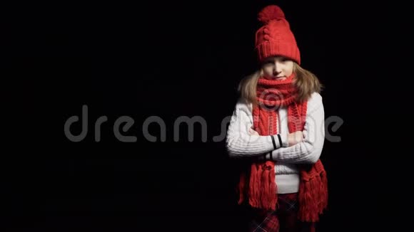 戴着针织冬帽和围巾看镜头的小女孩视频的预览图