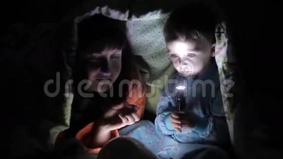 快乐的妈妈和孩子在被子下面玩平板电脑视频的预览图