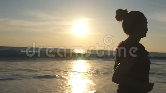 日出时沿着海岸慢跑的女孩日落时在海边奔跑的年轻女子剪影女性视频的预览图