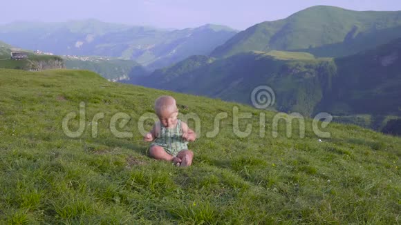 一岁的男孩学着走在群山的背景上视频的预览图
