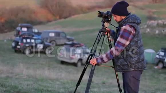 年轻的摄影师用相机和三角架在大自然中工作视频的预览图
