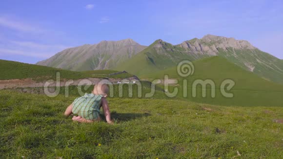 一岁的男孩学着走在群山的背景上视频的预览图