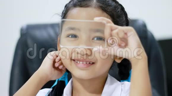 近镜头亚洲小女孩在泰国幼儿园学生制服使用Cleas玻璃就像智能手机的未来主义网络视频的预览图
