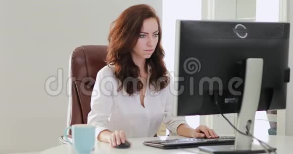 漂亮的女商人在办公室里看电脑显示器视频的预览图