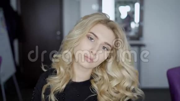 年轻的金发女郎为相机摆姿势一张漂亮的脸照片的近照时尚波型美发师视频的预览图
