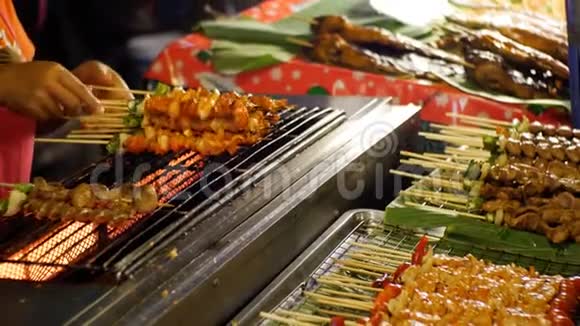 亚洲街头美食卖家在柜台上用蔬菜做成的木串上烤串视频的预览图