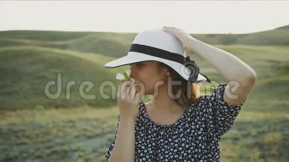 戴帽子的女人闻着一朵花视频的预览图