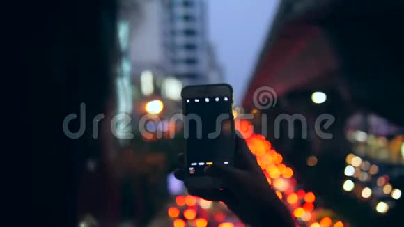年轻的Hipster旅游女孩采取智能手机图片在夜间曼谷城市汽车交通泰国4K视频的预览图