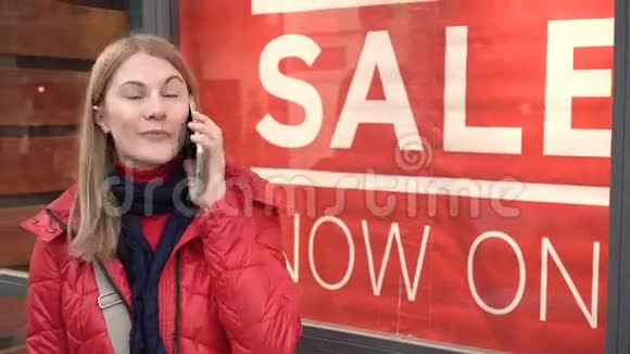 美丽迷人的年轻女子在橱窗附近和朋友交谈红色的冬衣销售标志视频的预览图