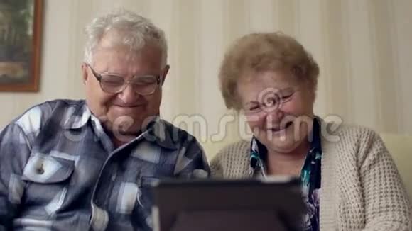 成熟的老夫妇享受现代技术使用平板电脑老年人在家里与互联网交流视频的预览图