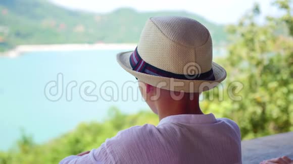 戴帽子的男孩从视野中眺望远处的大海和山脉看法视频的预览图