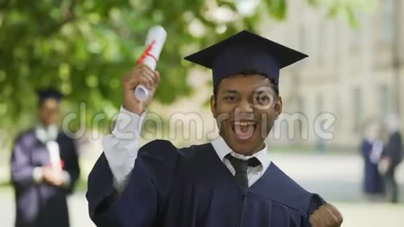 性格开朗的男毕业生带照相机和微笑证书成功视频的预览图