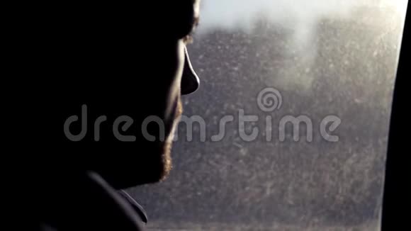 一个年轻人坐在靠近窗户的汽车上喝着铝罐里的啤酒捕捉到太阳的傍晚光线视频的预览图