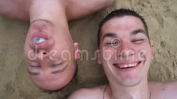 还有两个年轻人躺在海滩上嚼口香糖吹泡泡对着镜头微笑视频的预览图