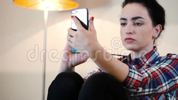 美丽的年轻白种人女士脖子上戴着耳机使用智能手机上的应用程序发短信视频的预览图