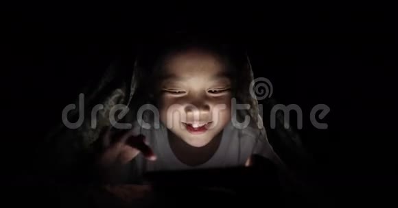 亚洲儿童夜间在床上玩平板电脑游戏视频的预览图