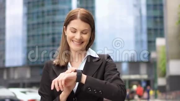 在市中心使用智能手表的女商人职业女性浏览聊天阅读新闻视频的预览图