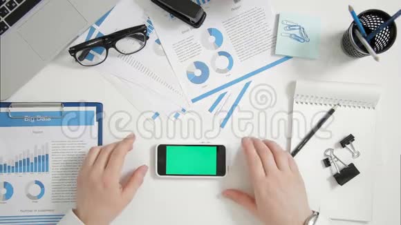商务人士坐在办公桌旁双手靠近绿色屏幕智能手机水平方向视频的预览图