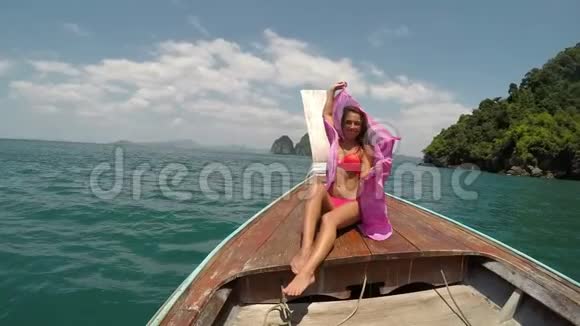 美丽的女人坐在泰国的船鼻动作镜头POV扬起粉红的帕雷奥女孩快乐的微笑视频的预览图