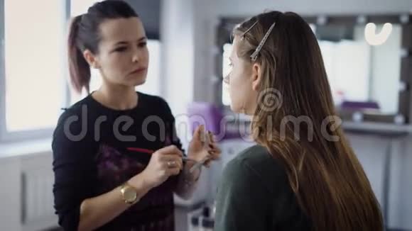 美容店化妆师训练学生进入决赛女孩把刷子放在荧光笔上视频的预览图