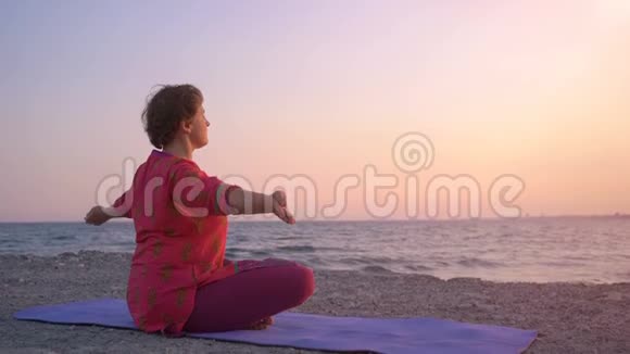女人在日出时坐着莲花姿势早上冥想瑜伽冥想的概念年轻女子练习瑜伽视频的预览图