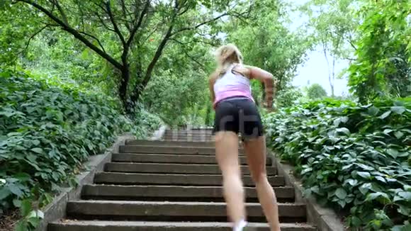 美丽的运动年轻金发女人跑楼上在森林公园在夏天进行练习视频的预览图