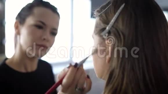 时尚界的专业化妆师正在化妆年轻模特她正坐在一张椅子上美容视频的预览图