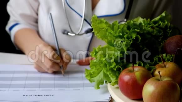 营养学家在满桌的水果和蔬菜上写饮食计划视频的预览图