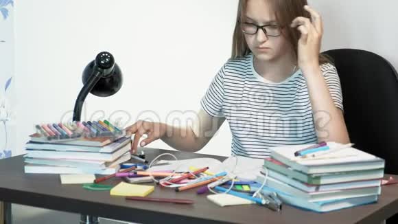 一个戴眼镜的十几岁女孩正坐在学校的办公桌前学习概念视频的预览图