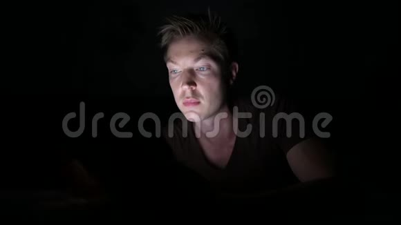 年轻英俊的斯堪的纳维亚人在黑暗的房间里使用数字平板电脑视频的预览图