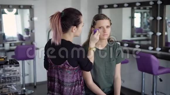 年轻模特在一家新的时装沙龙中首先来到专业化妆师一个染了头发的女孩仔细地视频的预览图