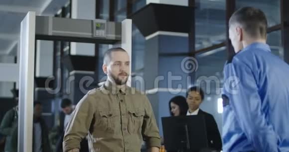 机场工人用金属探测器检查乘客视频的预览图