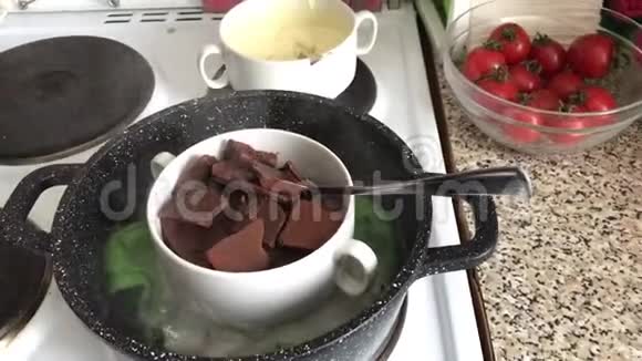 在炉子上的碗里放了一块黑白巧克力巧克力被融化在水浴中做甜点视频的预览图