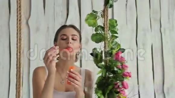 一个打扮得漂亮的女人在秋千上装饰着花吹泡泡视频的预览图