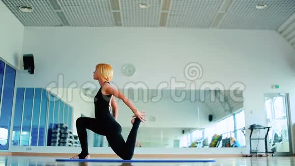 年轻女孩在垫子上的镜子附近练习瑜伽的柔韧性视频的预览图