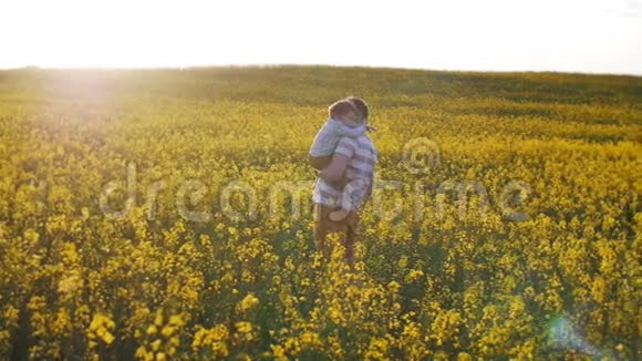 父亲把他的小儿子抱在田野上慢节奏视频的预览图