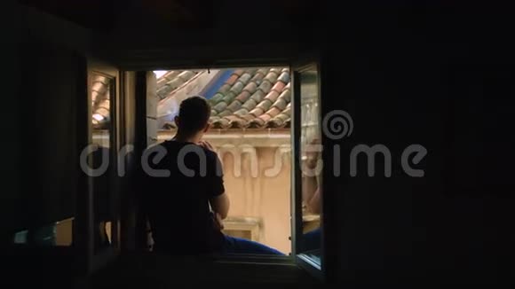 英俊的男人坐在窗台上视频的预览图