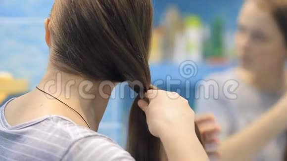 一个年轻的欧洲女人对着镜子编辫子视频的预览图